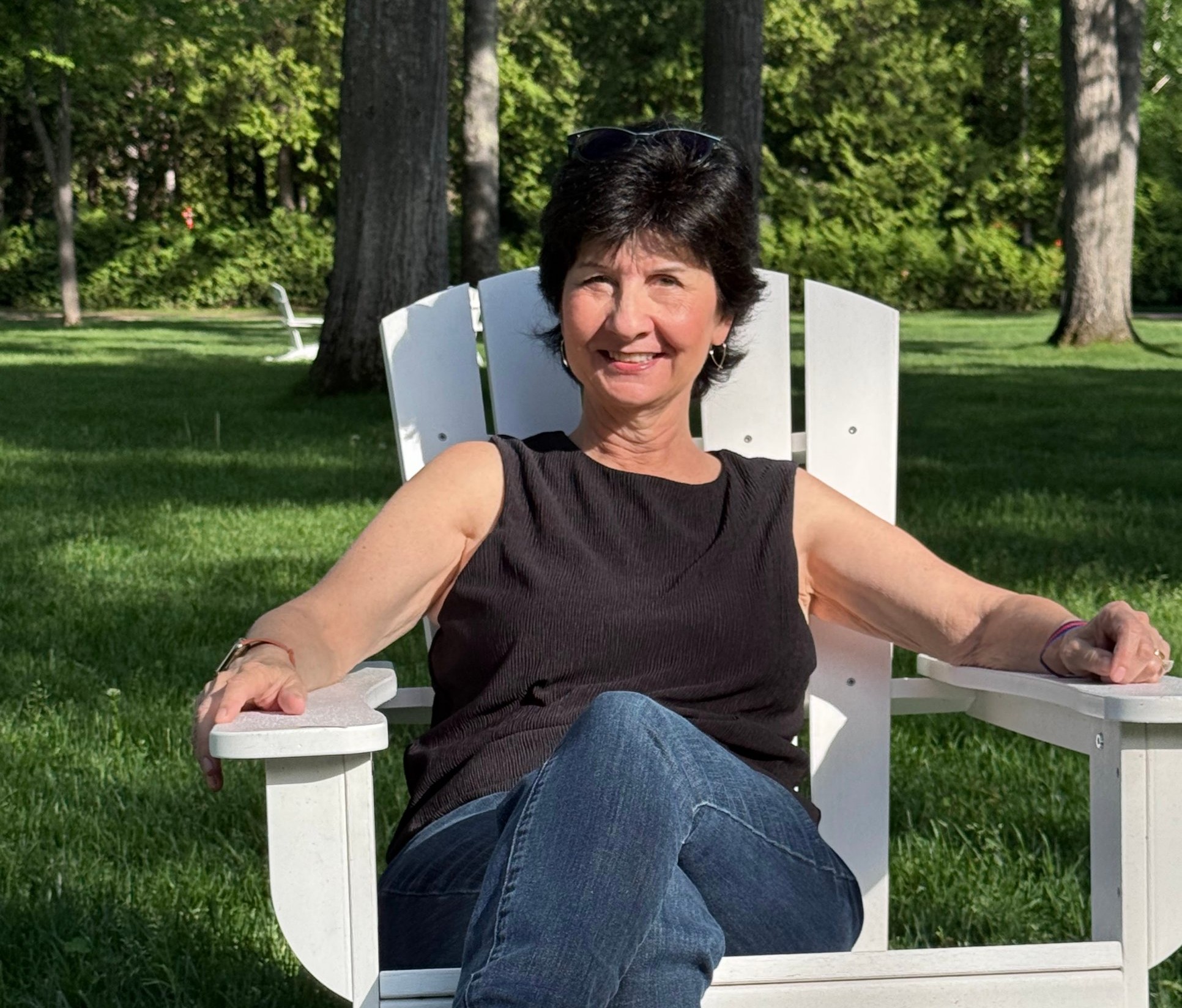 Linda L.M. Worley, MD, relaxing in a white Adirondack chair on a sunny lawn.